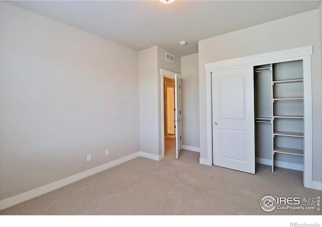 unfurnished bedroom featuring light colored carpet and a closet