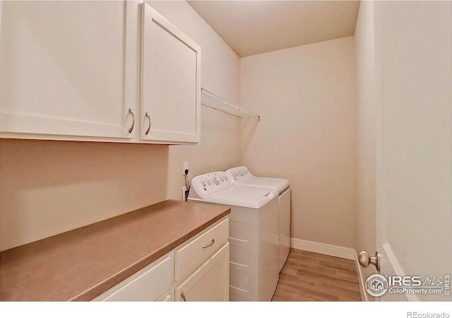 washroom with washer and clothes dryer, light hardwood / wood-style floors, and cabinets