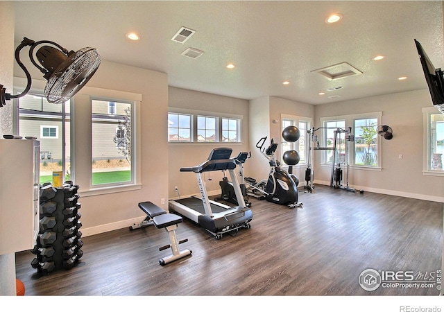 exercise room with plenty of natural light, dark wood-type flooring, and a textured ceiling