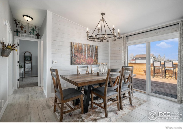 dining area with an inviting chandelier, wood-type flooring, vaulted ceiling, and wood walls