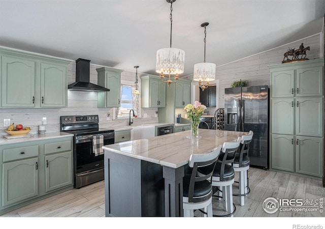 kitchen with appliances with stainless steel finishes, a center island, pendant lighting, and wall chimney exhaust hood