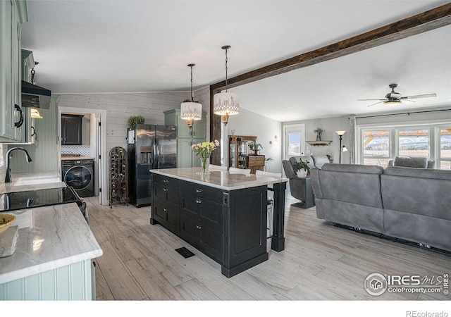 kitchen featuring a kitchen island, decorative light fixtures, washer / dryer, light hardwood / wood-style floors, and black fridge