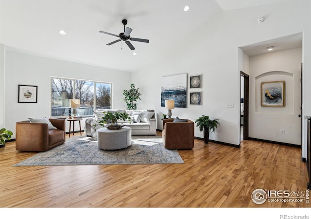 living room featuring ceiling fan, high vaulted ceiling, and light wood-type flooring