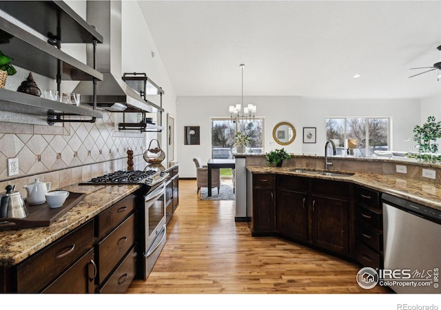 kitchen with extractor fan, sink, decorative light fixtures, appliances with stainless steel finishes, and decorative backsplash