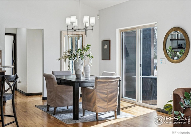 dining room featuring lofted ceiling, light hardwood / wood-style floors, and a notable chandelier