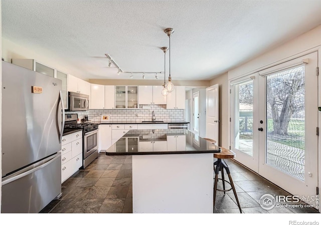 kitchen with a breakfast bar, decorative light fixtures, a center island, stainless steel appliances, and white cabinets