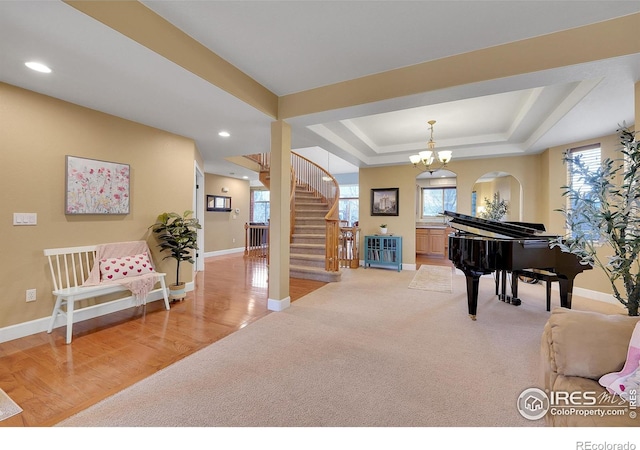 interior space with an inviting chandelier, a raised ceiling, and carpet flooring