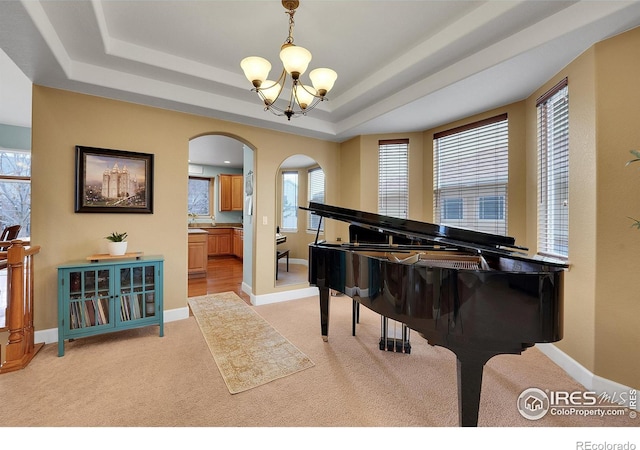 misc room featuring a tray ceiling, light carpet, and a notable chandelier