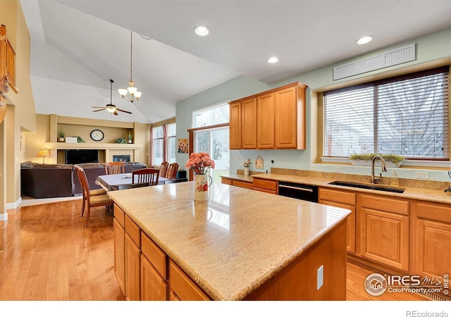 kitchen featuring lofted ceiling, sink, a center island, hanging light fixtures, and light wood-type flooring