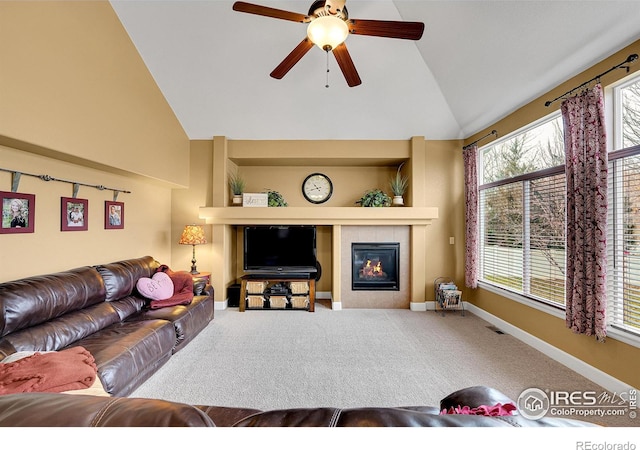 living room featuring ceiling fan, a tiled fireplace, vaulted ceiling, and carpet