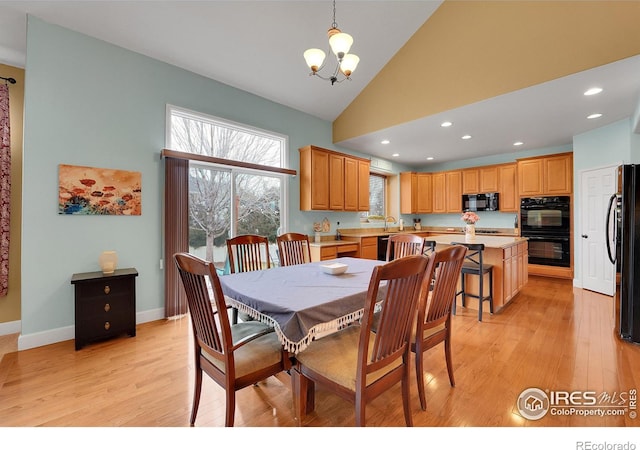 dining area with a notable chandelier, high vaulted ceiling, sink, and light wood-type flooring