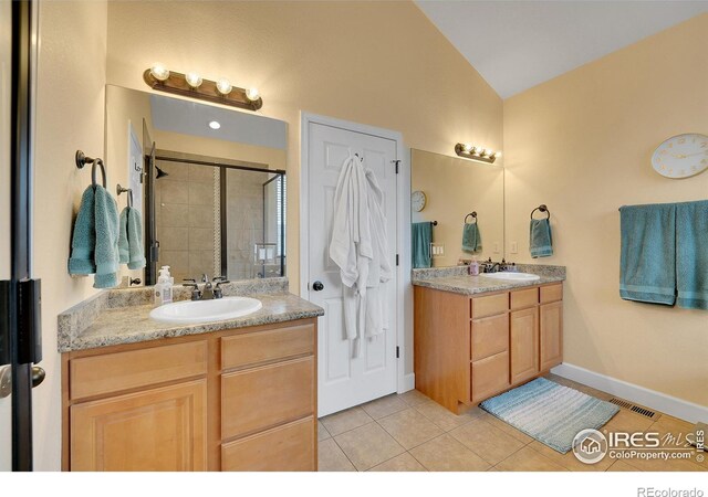 bathroom with vanity, vaulted ceiling, tile patterned floors, and walk in shower