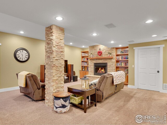 living room with ornate columns, a stone fireplace, and light colored carpet