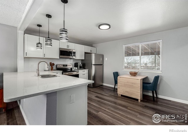 kitchen featuring decorative light fixtures, sink, white cabinets, kitchen peninsula, and stainless steel appliances