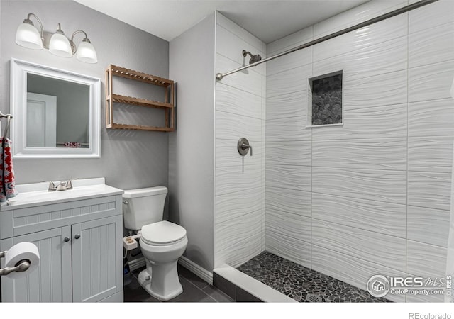 bathroom with tiled shower, vanity, and toilet