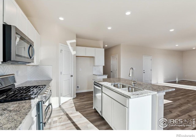 kitchen with sink, stainless steel appliances, an island with sink, and white cabinets