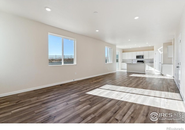 unfurnished living room featuring sink and dark hardwood / wood-style flooring