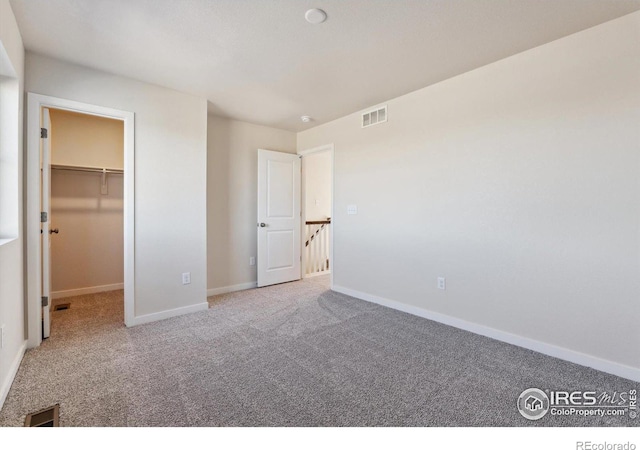 unfurnished bedroom with carpet and a spacious closet