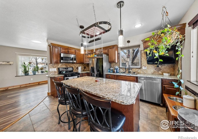 kitchen with appliances with stainless steel finishes, a center island, sink, and hanging light fixtures