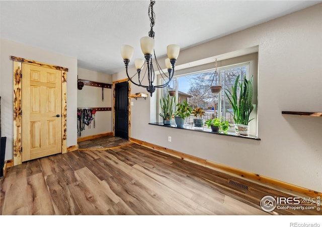 unfurnished dining area with wood-type flooring and a chandelier