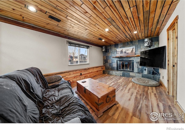 living room with wood-type flooring, a stone fireplace, and wooden ceiling