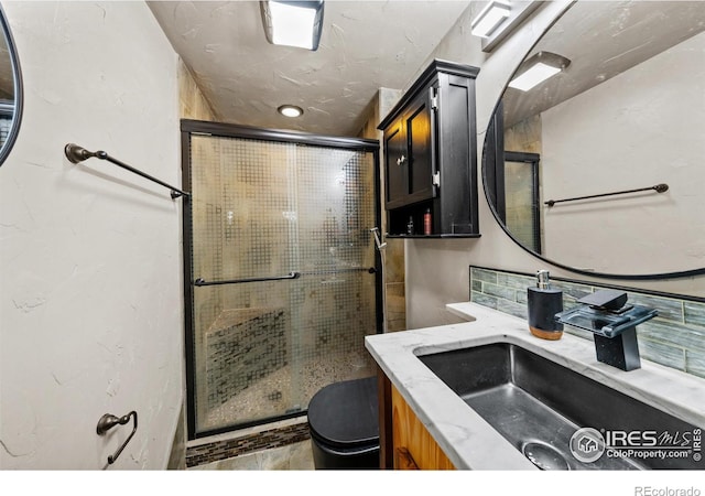 bathroom with a shower with door, vanity, and toilet