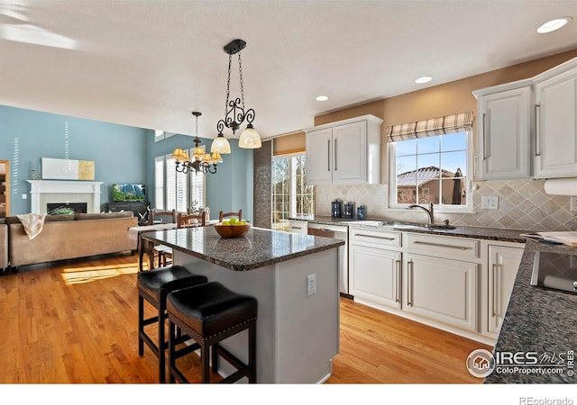 kitchen featuring white cabinetry, a breakfast bar, a center island, and light wood-type flooring