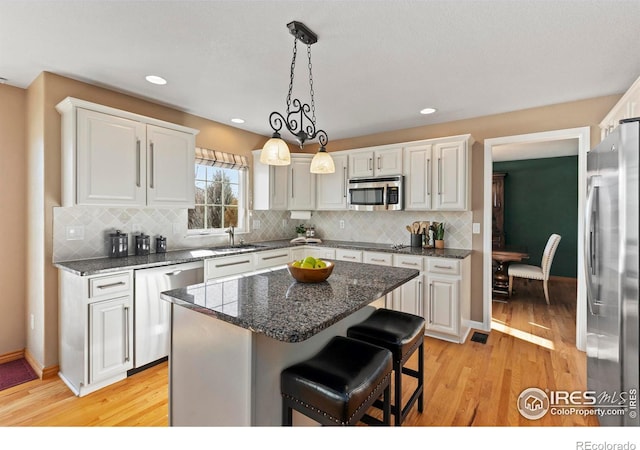 kitchen featuring white cabinetry, stainless steel appliances, a breakfast bar, and a kitchen island