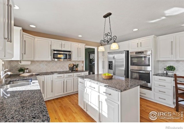 kitchen featuring a kitchen island, white cabinetry, sink, stainless steel appliances, and light wood-type flooring