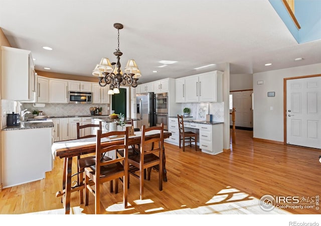 dining room with a chandelier, sink, and light hardwood / wood-style flooring