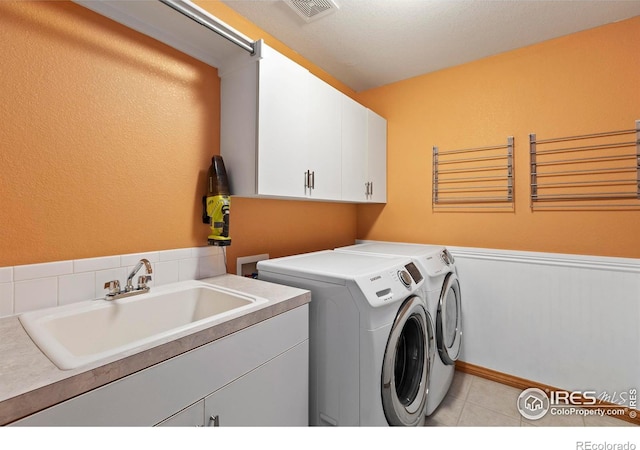 laundry room with cabinets, washer and dryer, sink, and light tile patterned floors