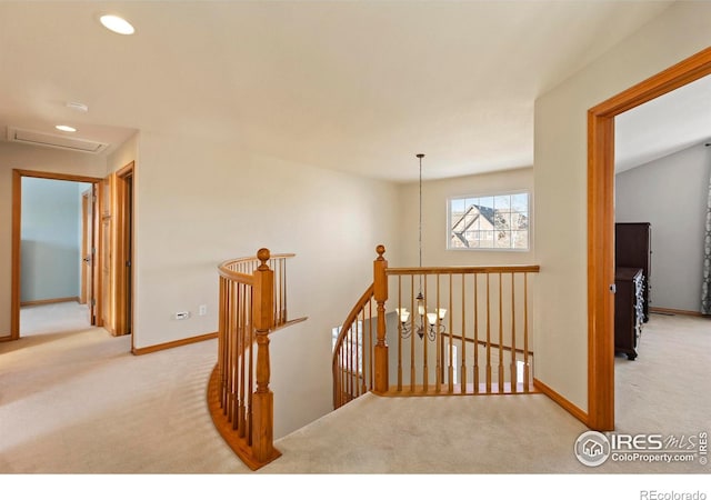 hall featuring light colored carpet and an inviting chandelier