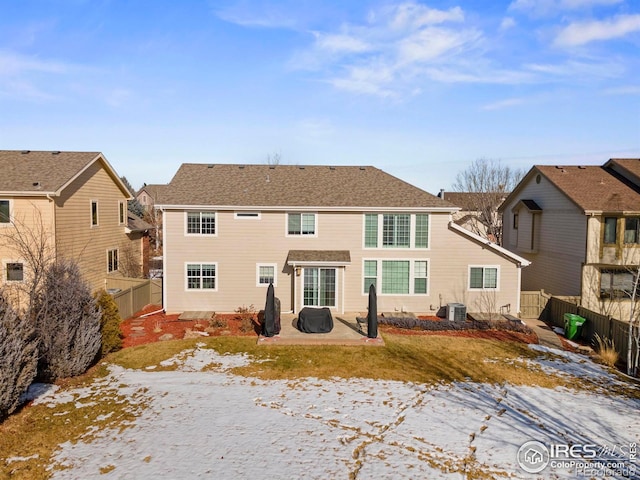 snow covered rear of property featuring central AC and a patio area