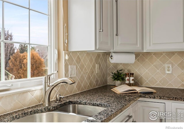 kitchen featuring tasteful backsplash, dark stone counters, sink, and white cabinets