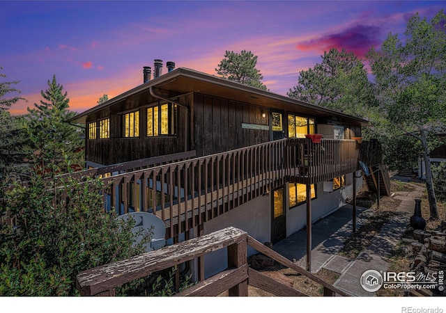 back house at dusk featuring a wooden deck