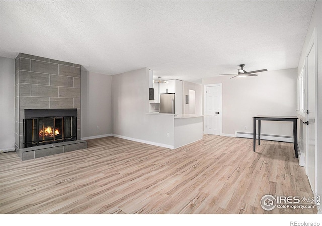 unfurnished living room with ceiling fan, a fireplace, a textured ceiling, a baseboard radiator, and light wood-type flooring