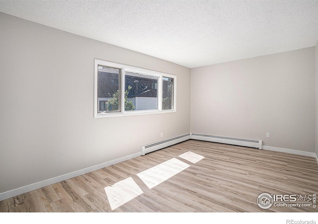 spare room featuring light wood-type flooring, a textured ceiling, and baseboard heating