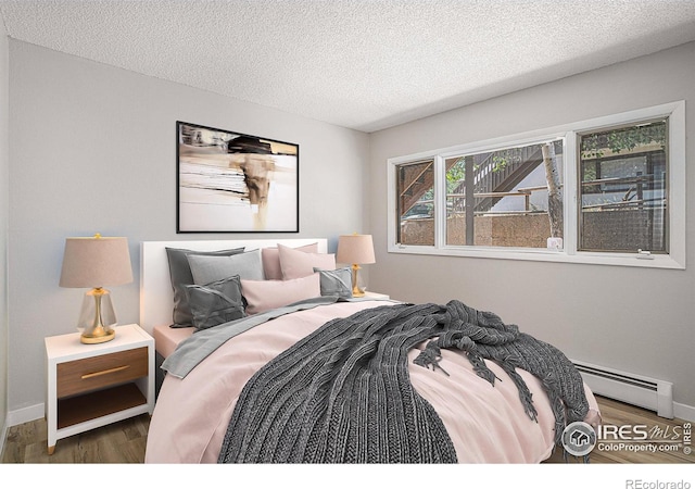 bedroom featuring a textured ceiling, dark hardwood / wood-style flooring, and baseboard heating