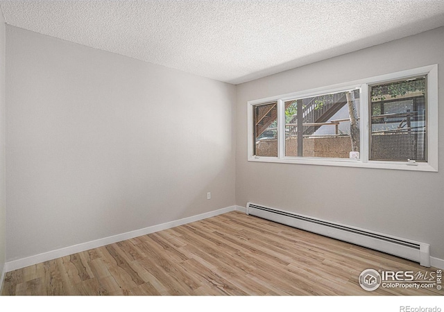 unfurnished room with baseboard heating, light hardwood / wood-style flooring, and a textured ceiling