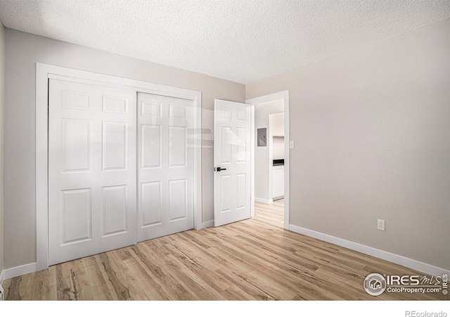 unfurnished bedroom with a closet, light hardwood / wood-style flooring, and a textured ceiling