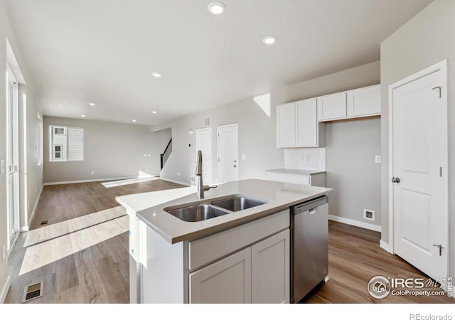 kitchen with white cabinetry, an island with sink, dishwasher, sink, and light hardwood / wood-style flooring