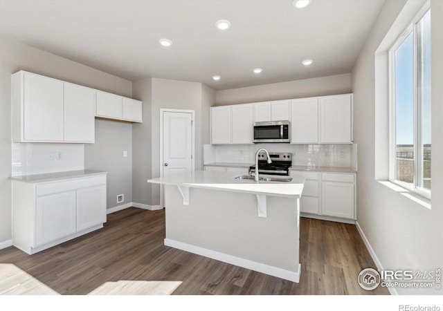 kitchen with stainless steel appliances, sink, a kitchen island with sink, and white cabinets