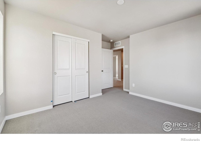 unfurnished bedroom featuring a closet and light carpet