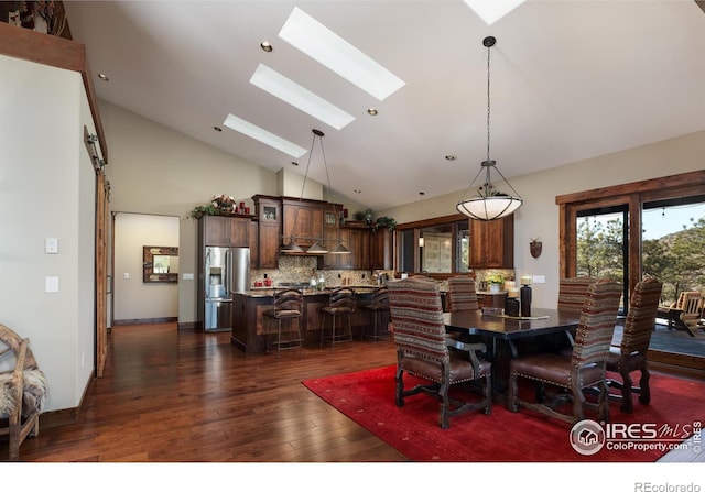 dining space featuring dark wood-type flooring, a skylight, and high vaulted ceiling