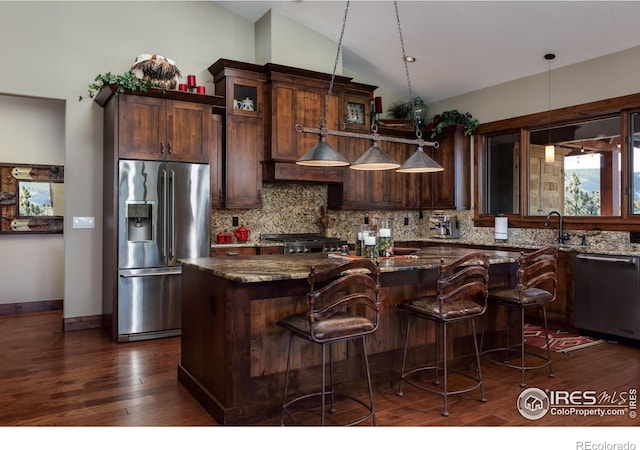 kitchen featuring pendant lighting, stainless steel appliances, dark stone counters, and a kitchen island