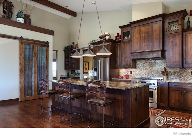 kitchen with appliances with stainless steel finishes, a barn door, a center island, and dark stone counters