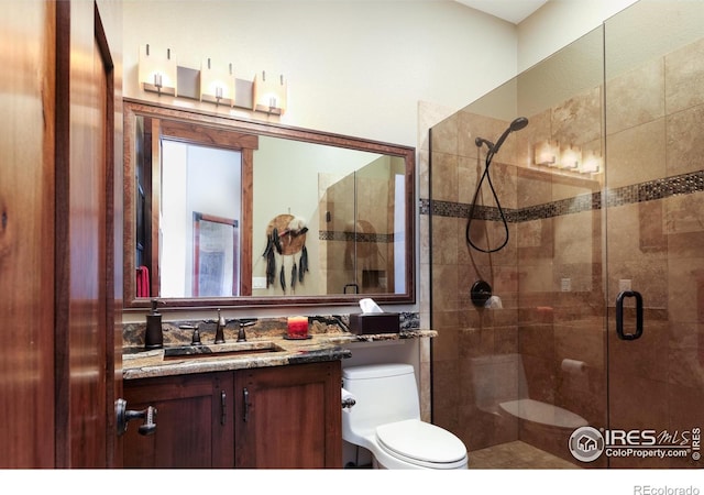 bathroom with vanity, a shower with shower door, and toilet