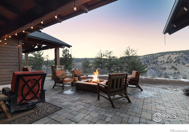 patio terrace at dusk with a gazebo, a mountain view, and an outdoor fire pit