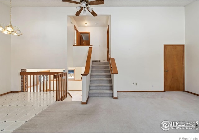 empty room with a towering ceiling, light colored carpet, and a chandelier