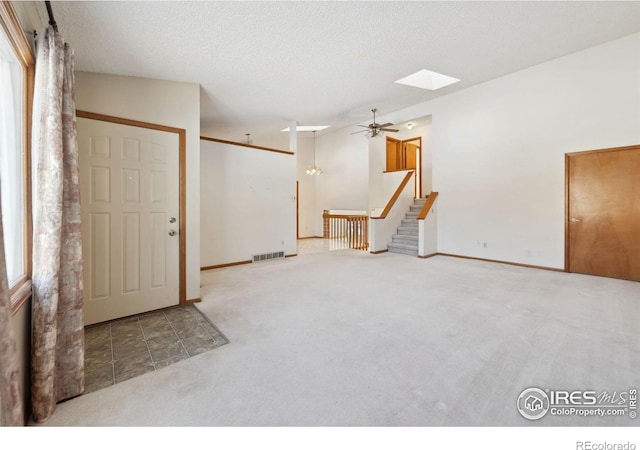 carpeted entryway with ceiling fan, a skylight, and a textured ceiling